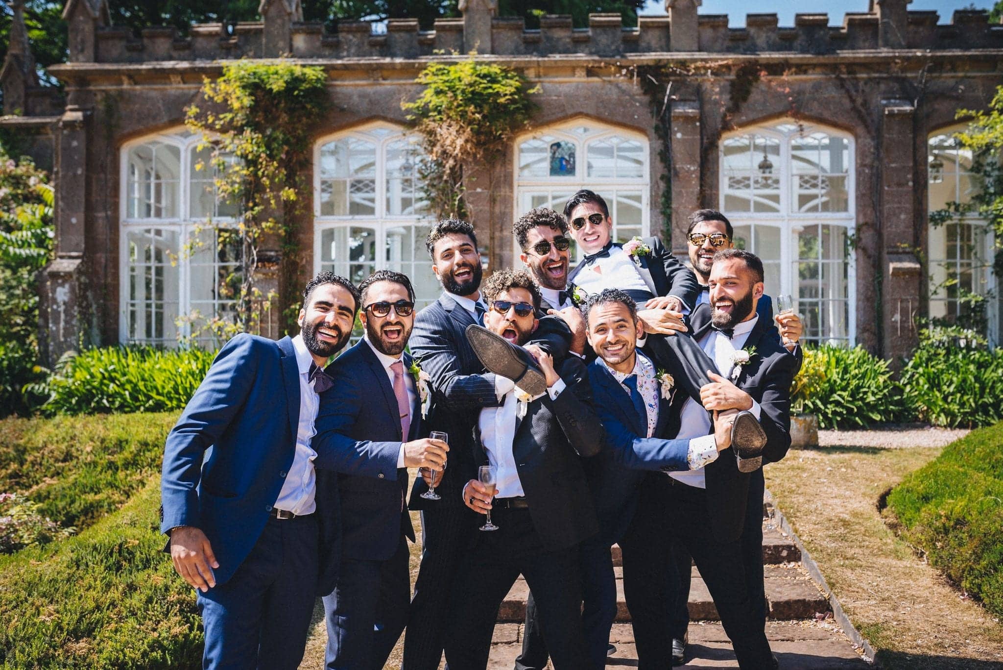 Groomsmen carrying the groom on their shoulders and laughing at a glamorous St Audries Park Wedding