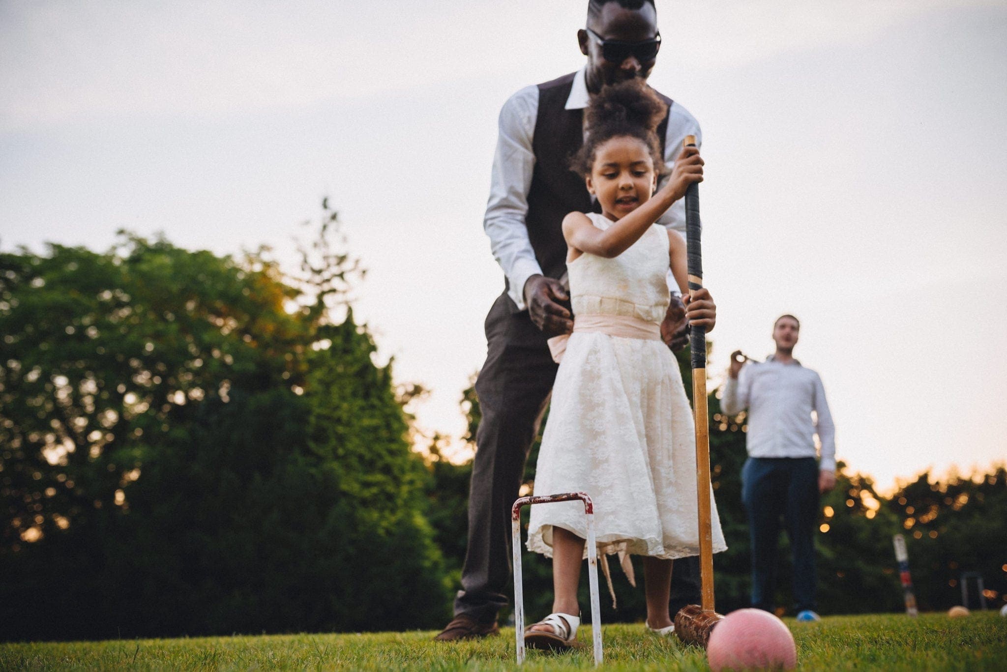 Wedding guest helping his daughter play croquet at St Audries Park