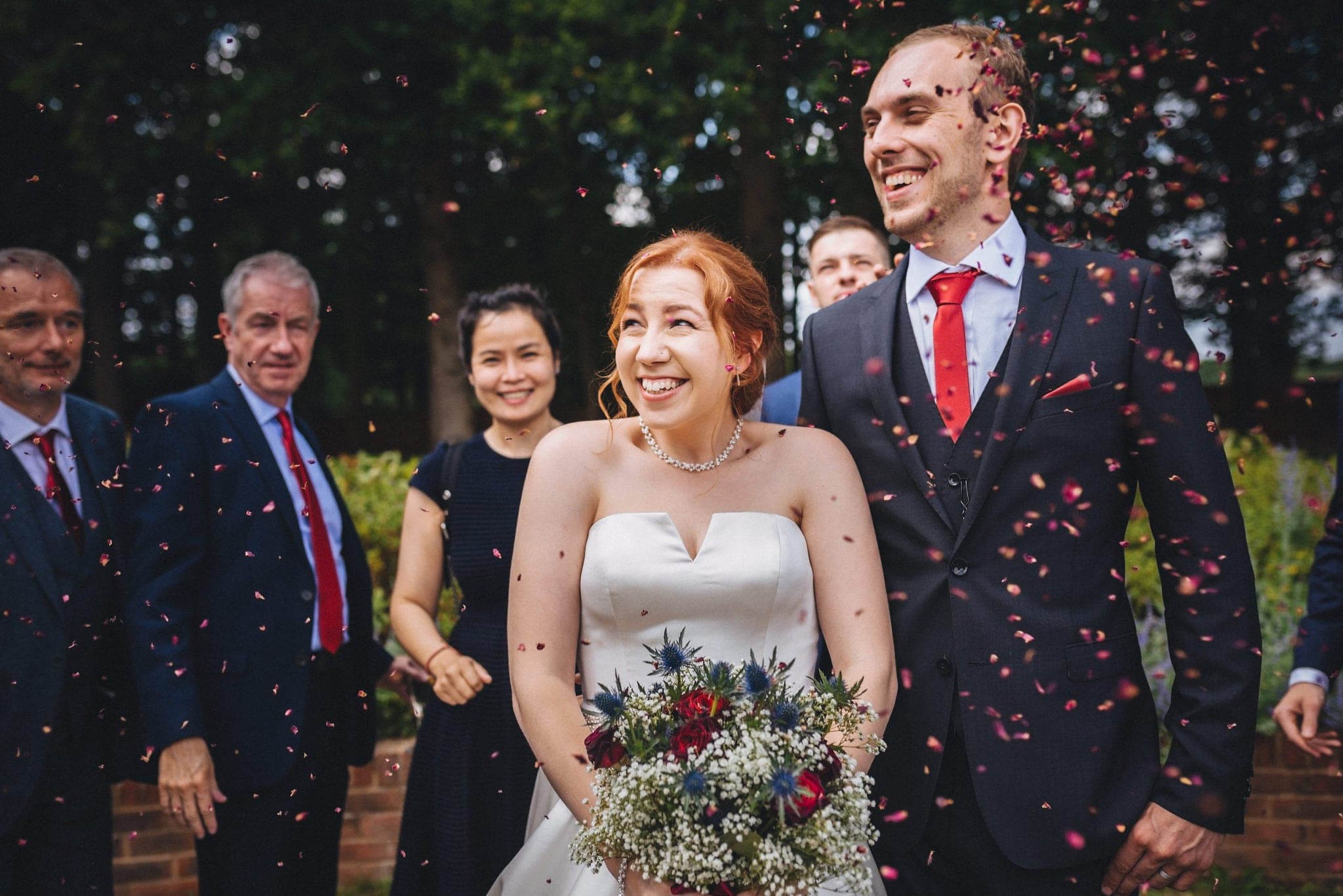 Bride and groom showered in red petal confetti at their Intimate Hever Hotel Wedding