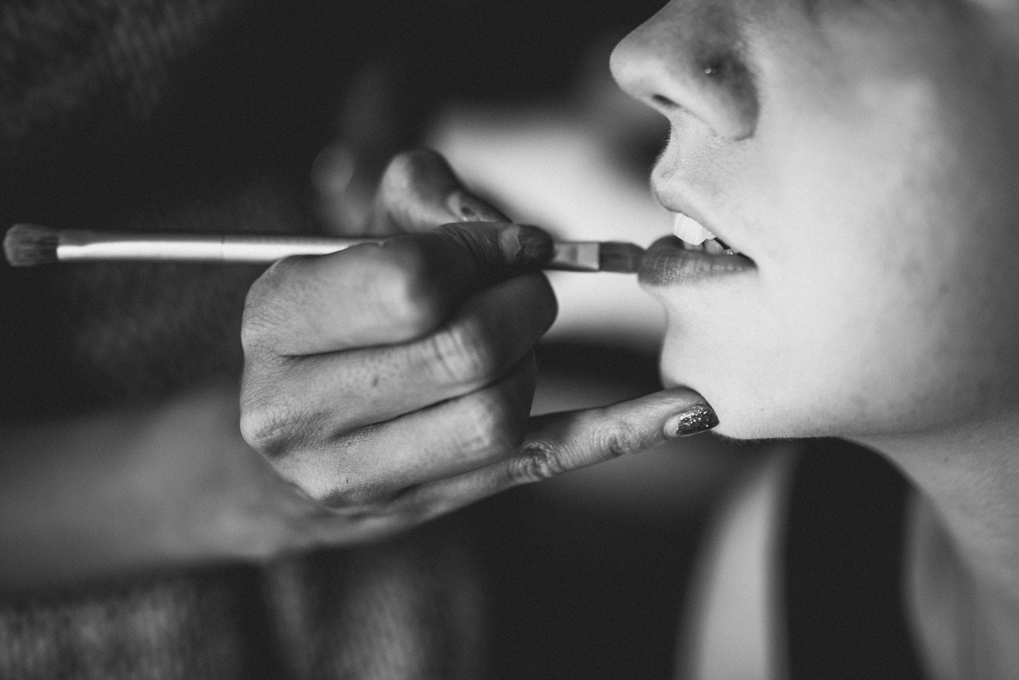 Black and white shot of bride having lipstick applied