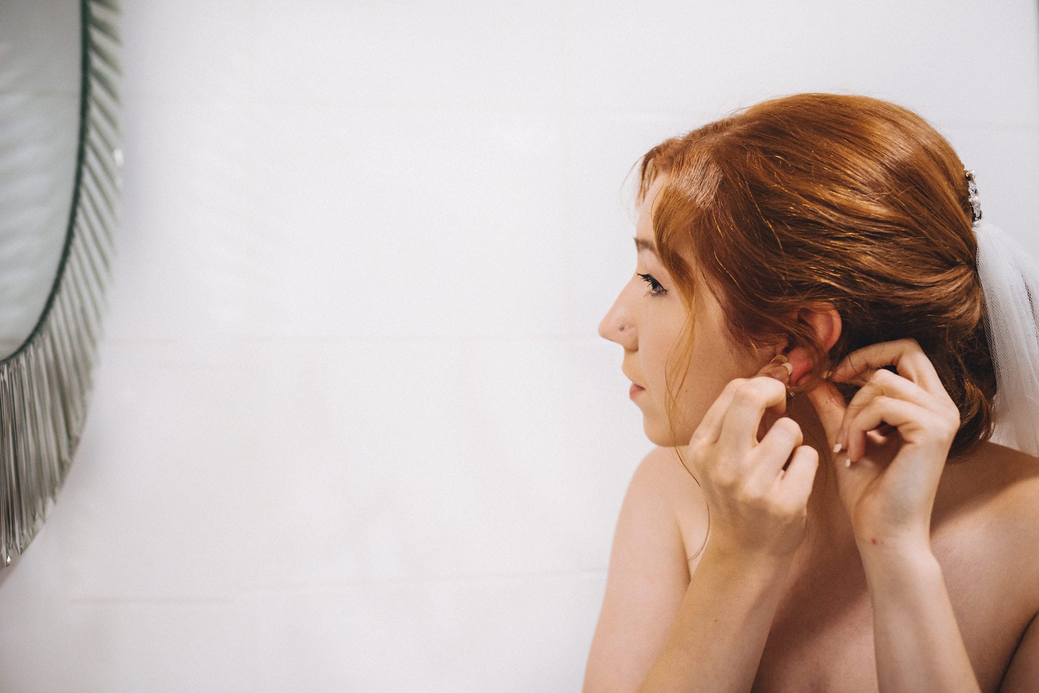 Bride fastens earring at her Hever Hotel Wedding preparations