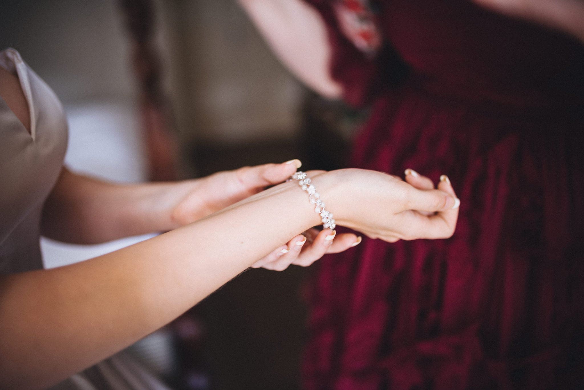 Bride fastens pearl bracelet as she gets ready for her intimate Hever Hotel wedding