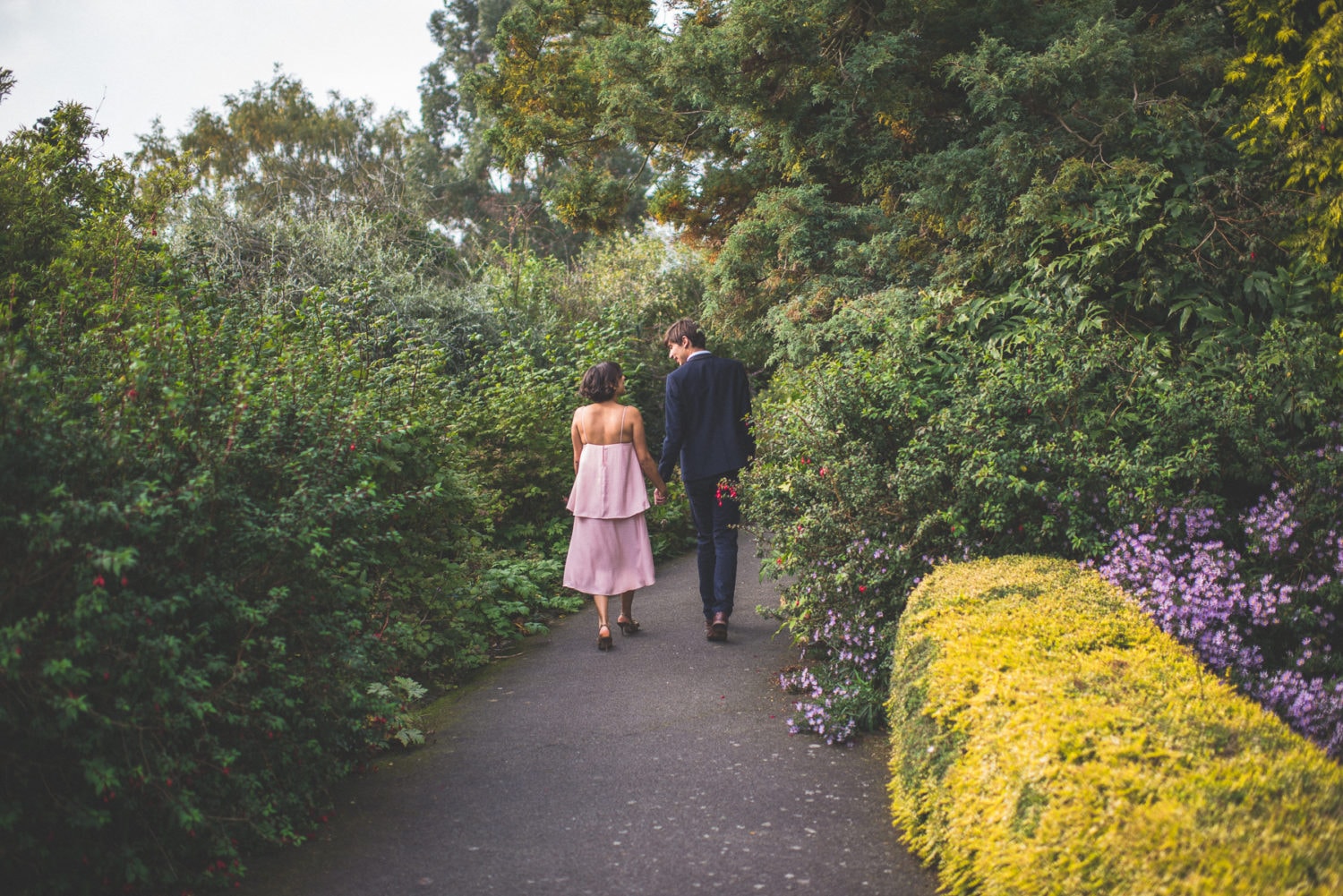 engaged couple walk down a colourful alley at a Hampstead pergola wedding