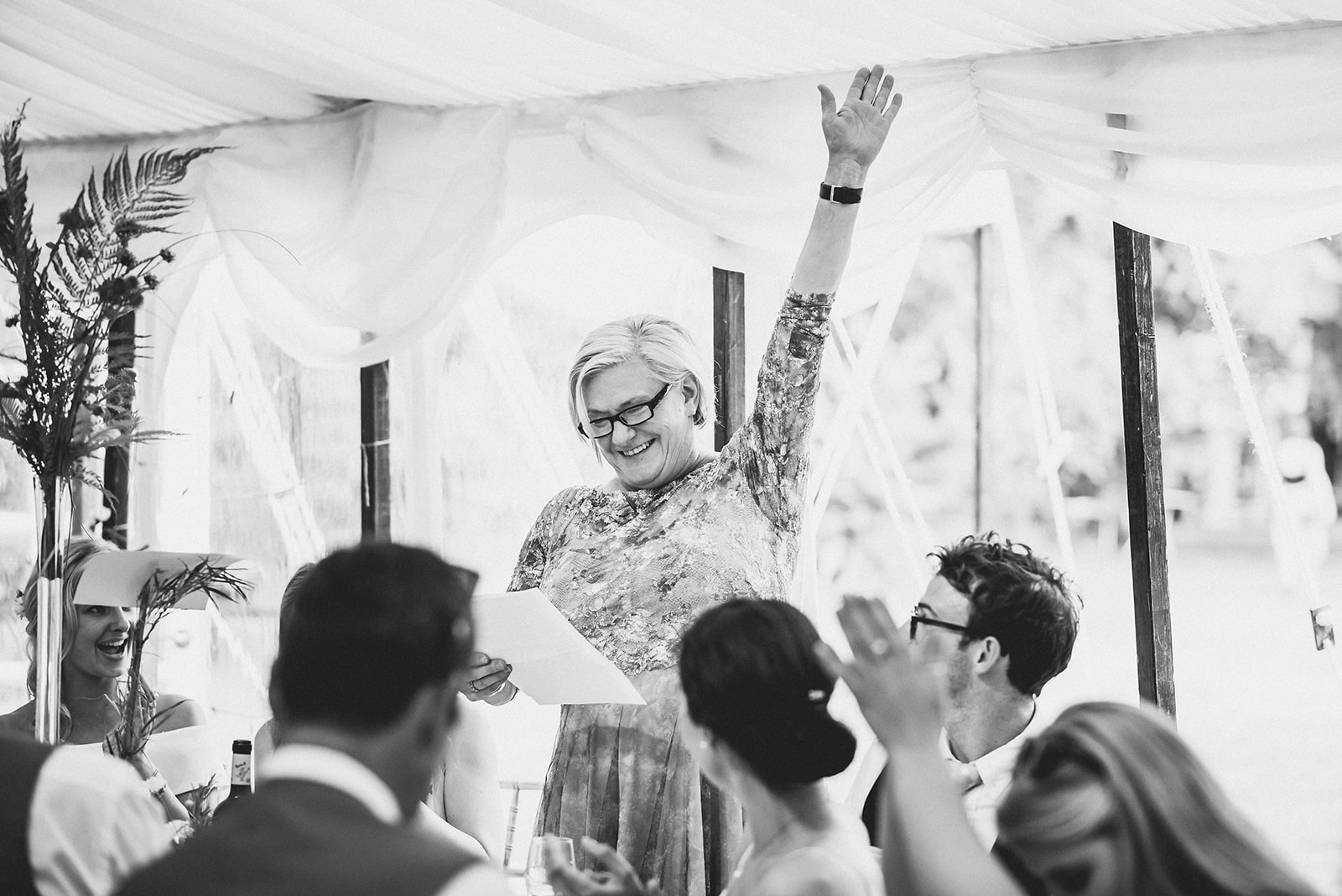 Mother of the groom cheering with her hand up during her wedding speech