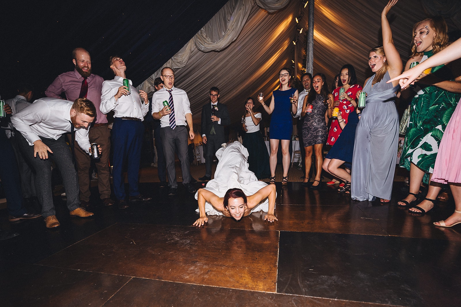 Bride doing the worm on the dance floor at her joyful cambridge farm marquee wedding