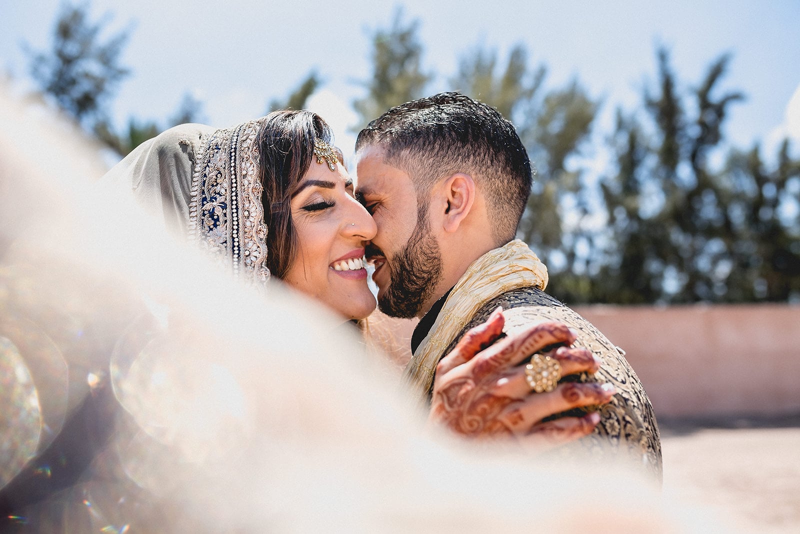 Moroccan Bride and groom laugh with each other while the wind blows through her wedding head scarf in Morocco