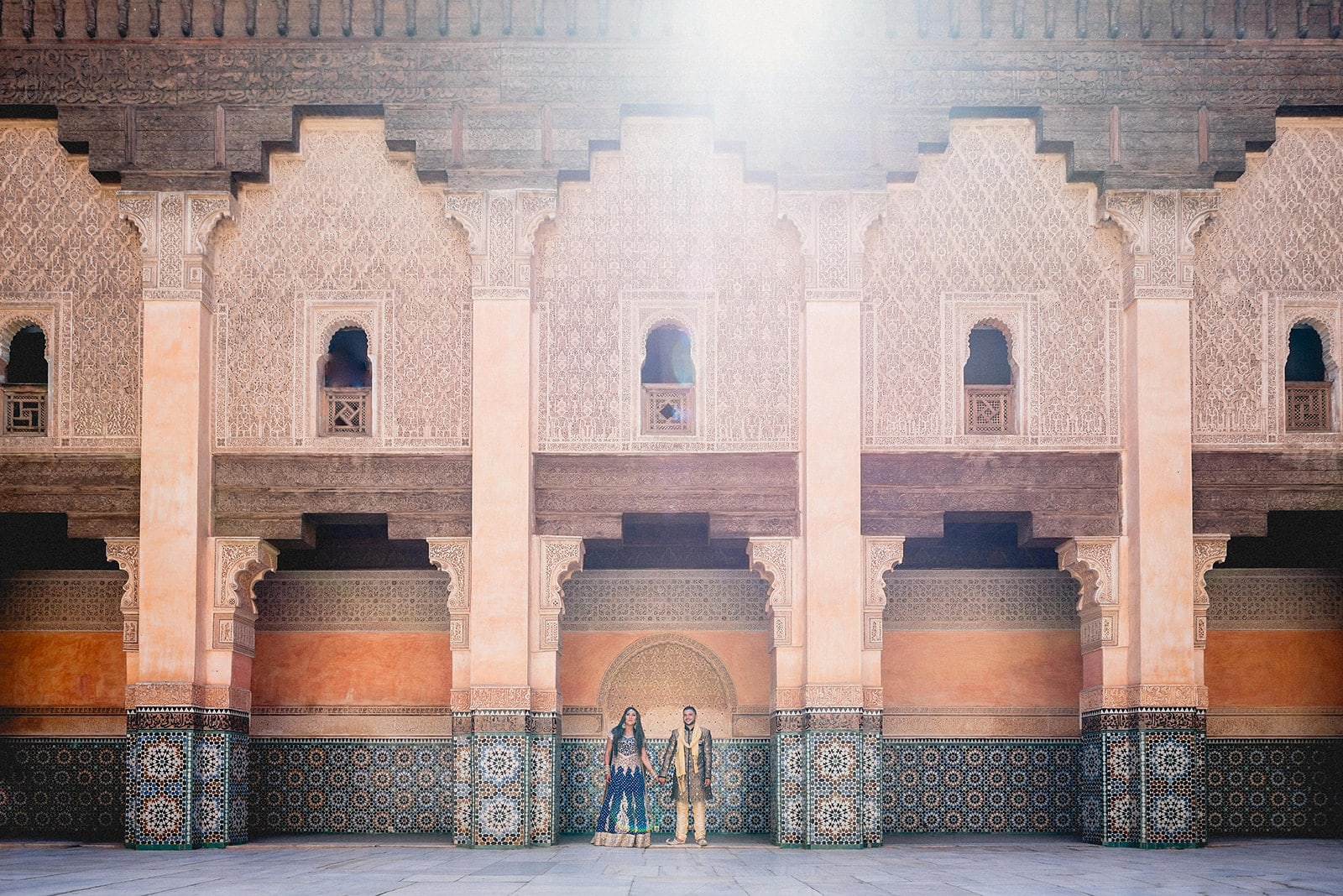 Bride and Groom holding hands in the central arch at the Ben Youssef Madrassa at their Moroccan Destination Wedding in Marrakech