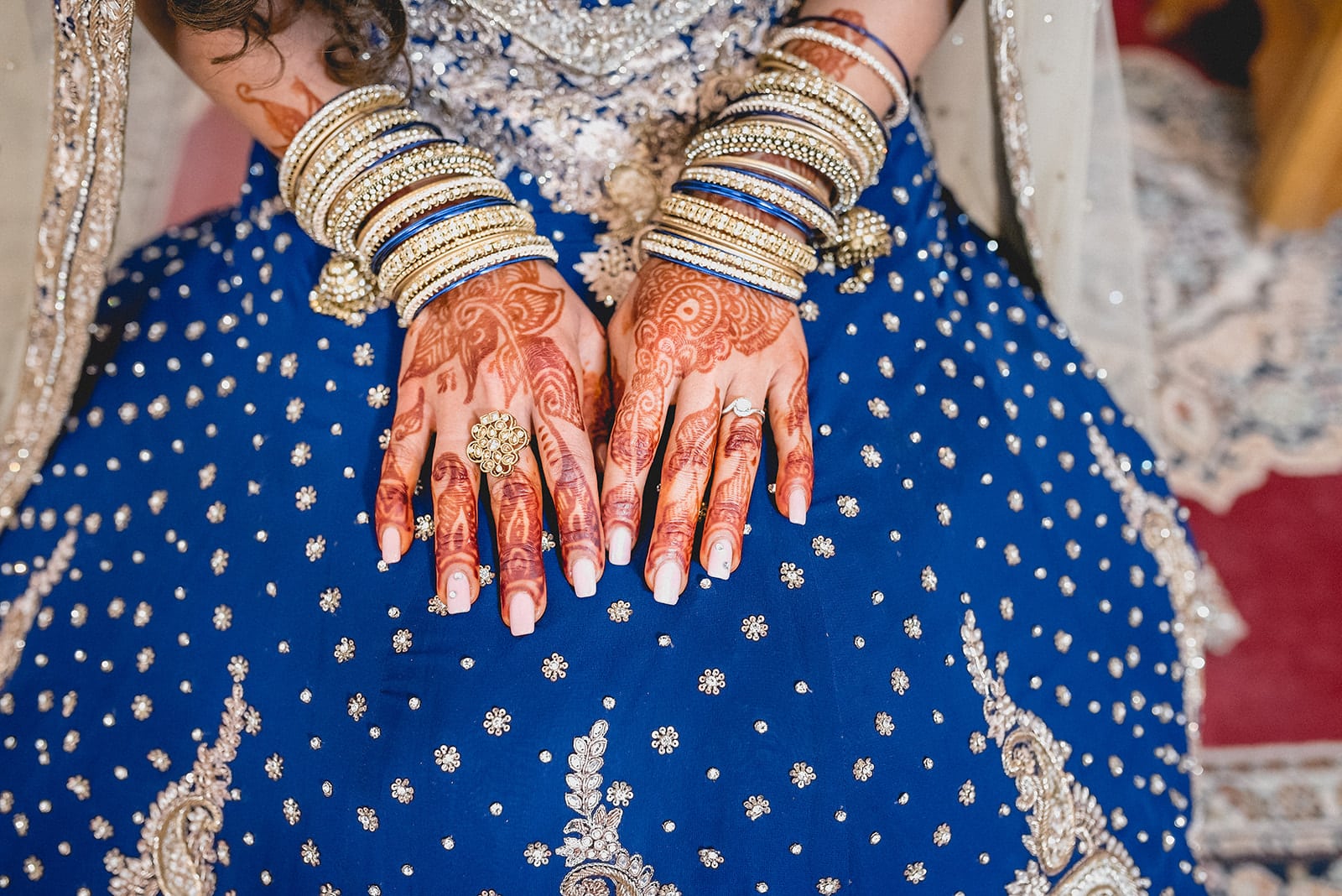 Bride's henna painted hands lying in her lap with traditional wedding bands