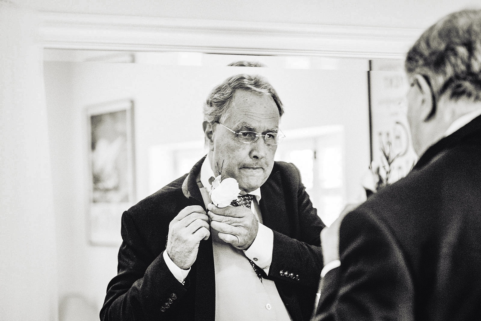 The father of the bride putting on his white rose boutonnière