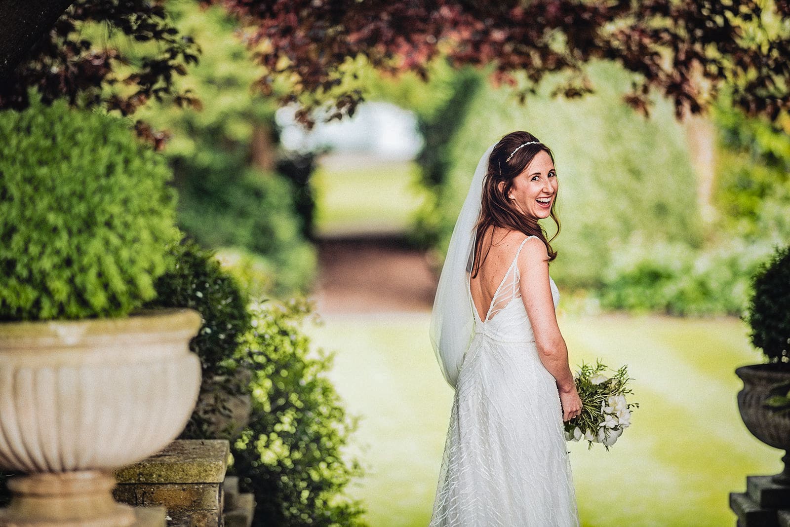 Bride laughs over her shoulder at her summer Hurlingham Club wedding