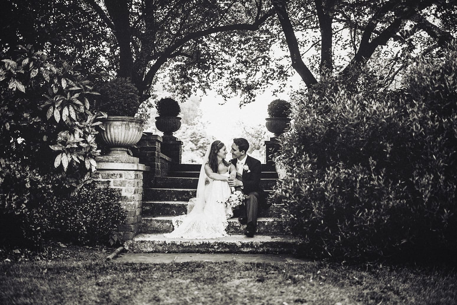 Bride and groom sit on the steps at the Hurlingham Club's sunken garden