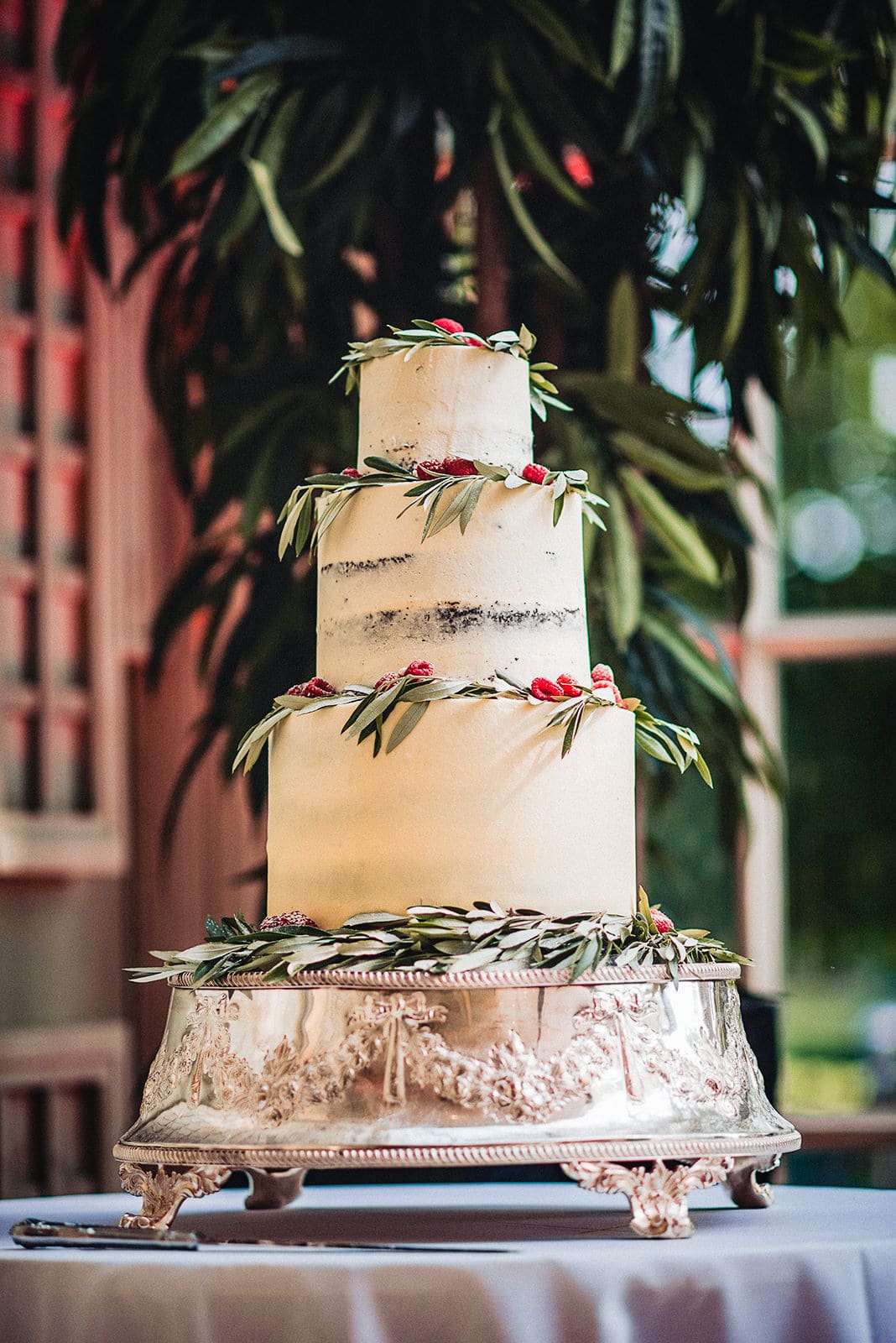 Semi-naked wedding cake with eucalyptus leaves and fresh raspberries