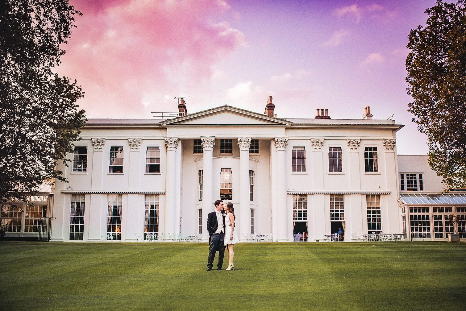 Bride and groom standing on the green at sunset at the Hurlingham Club