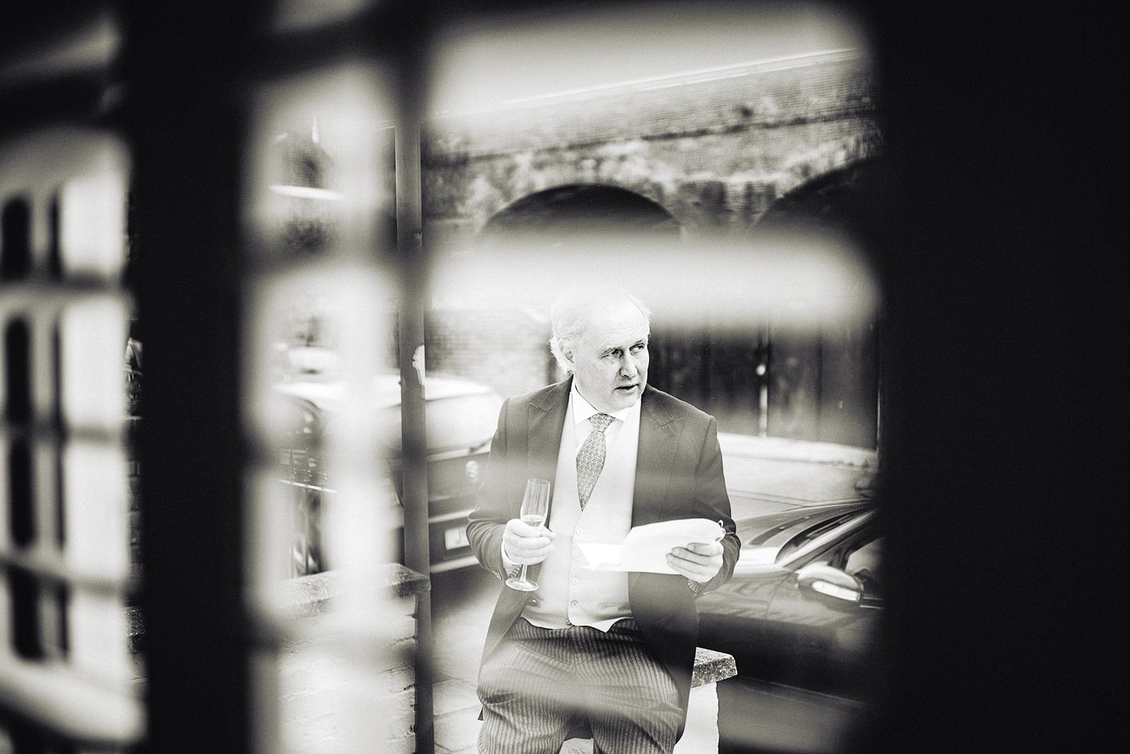 Father of the bride practicing his wedding speech seen through a shuttered window