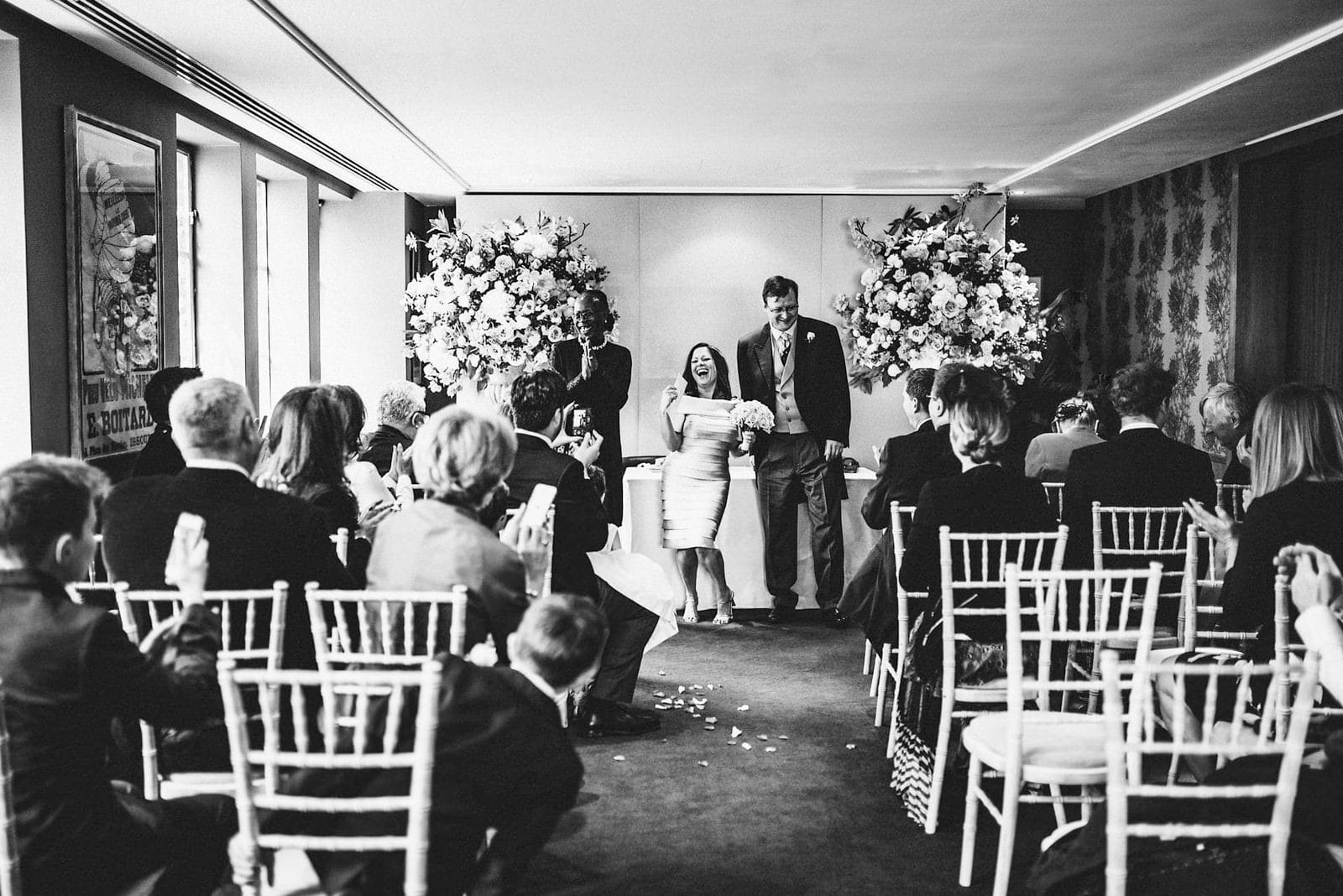 Bride laughs as she holds the marriage certificate at Chelsea's Bluebird