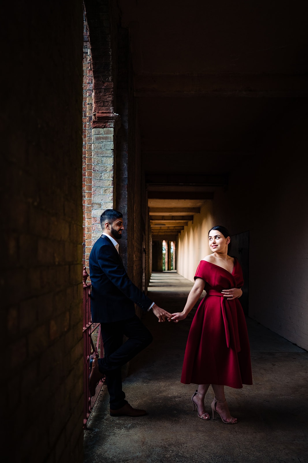 Asian couple hold hands in the arched pathway at the Hampstead Pergola and Gardens in London