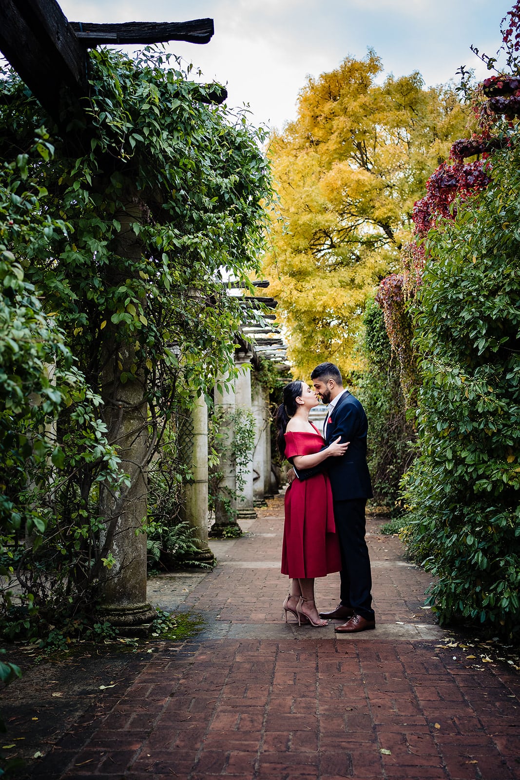 Couple kiss in the column-framed walkway at London's Hill Gardens and Pergola