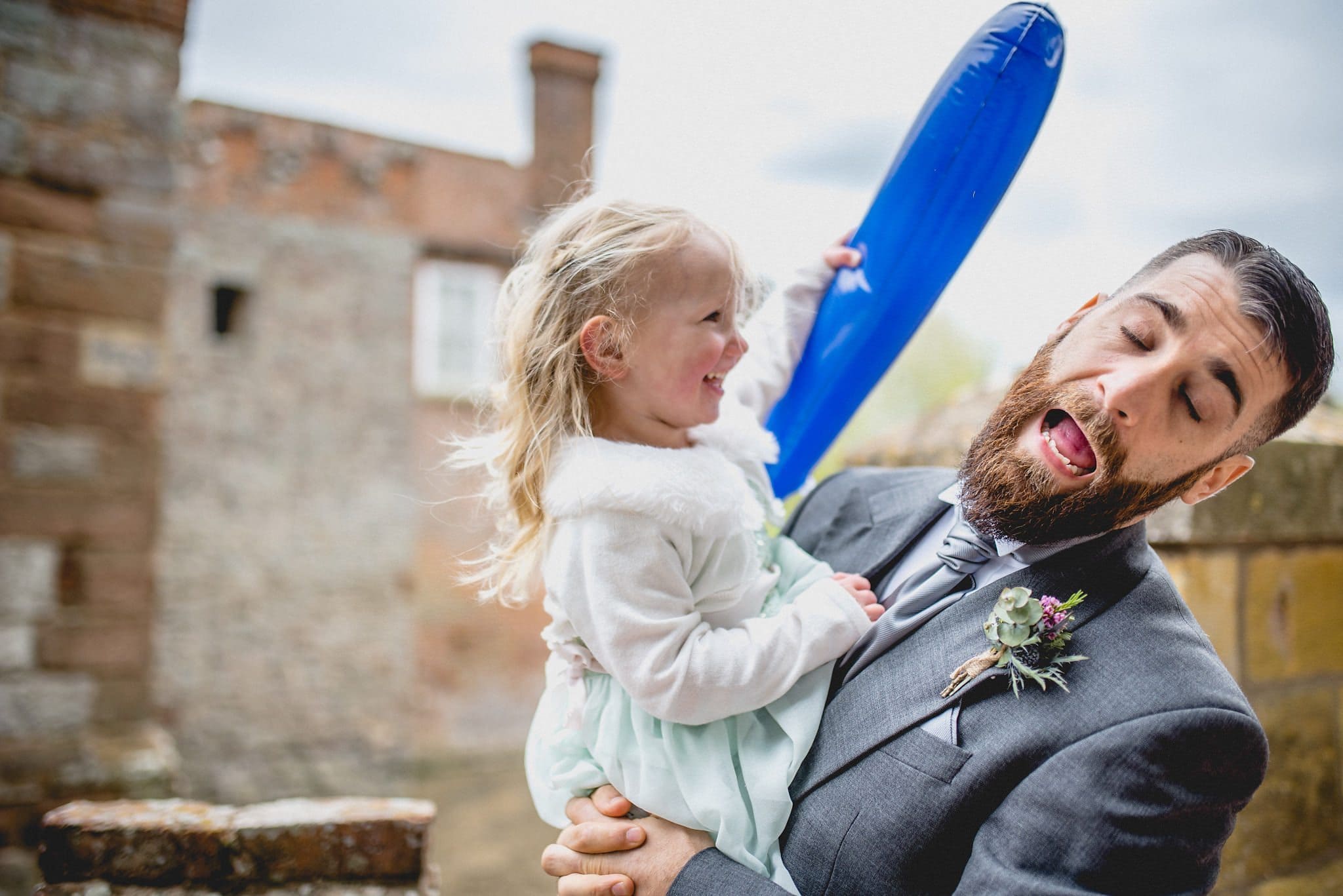 Little girl jokingly hitting a groomsman with a balloon