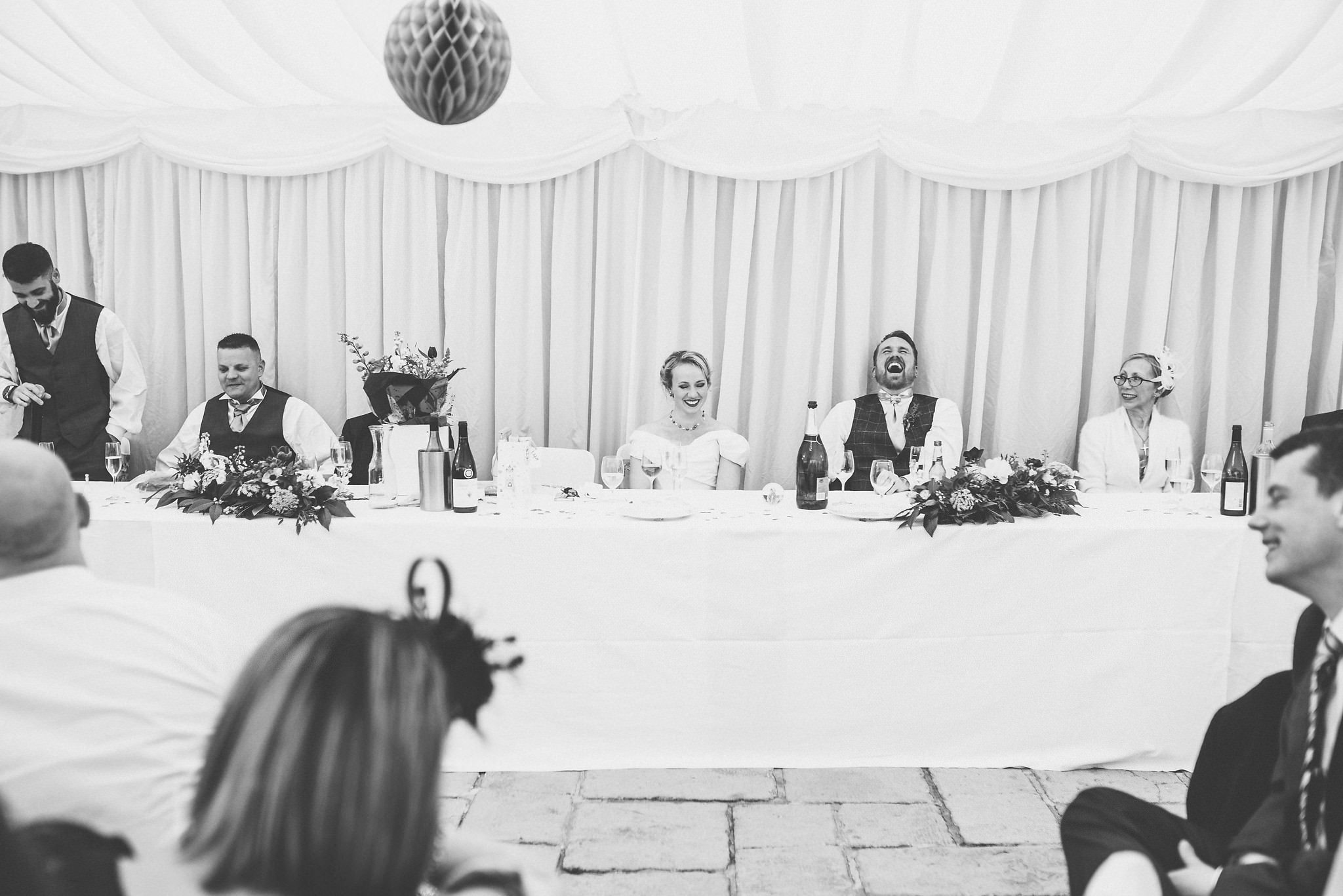 Bride and groom laughing loudly during their speeches at Birtsmorton Court