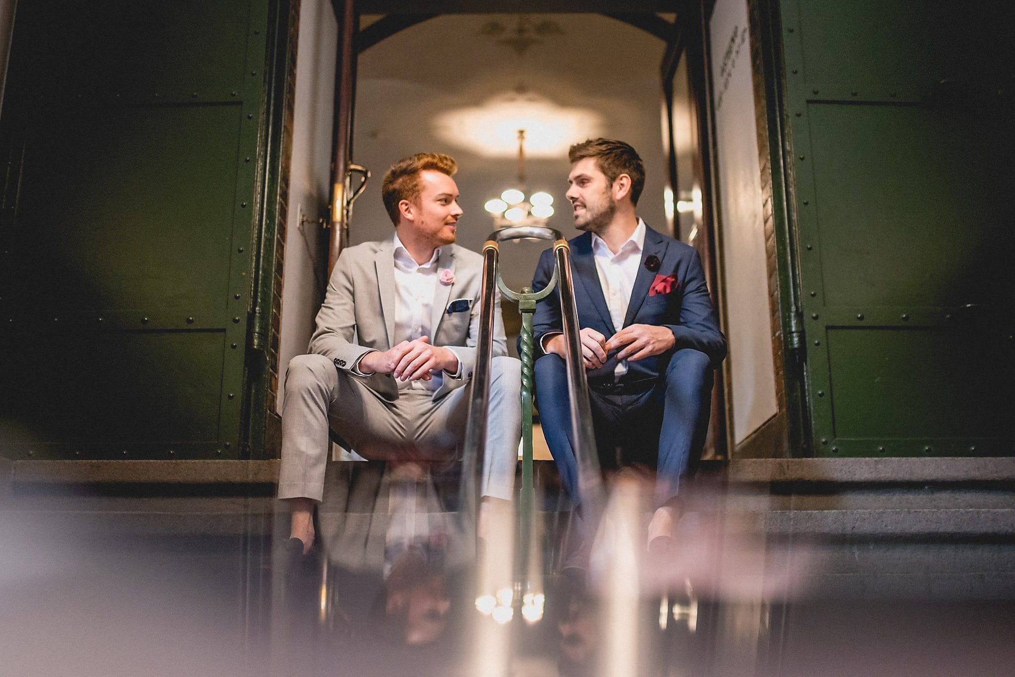 Same-sex couple sits on the steps of the Copenhagen Rådhus before their wedding ceremony
