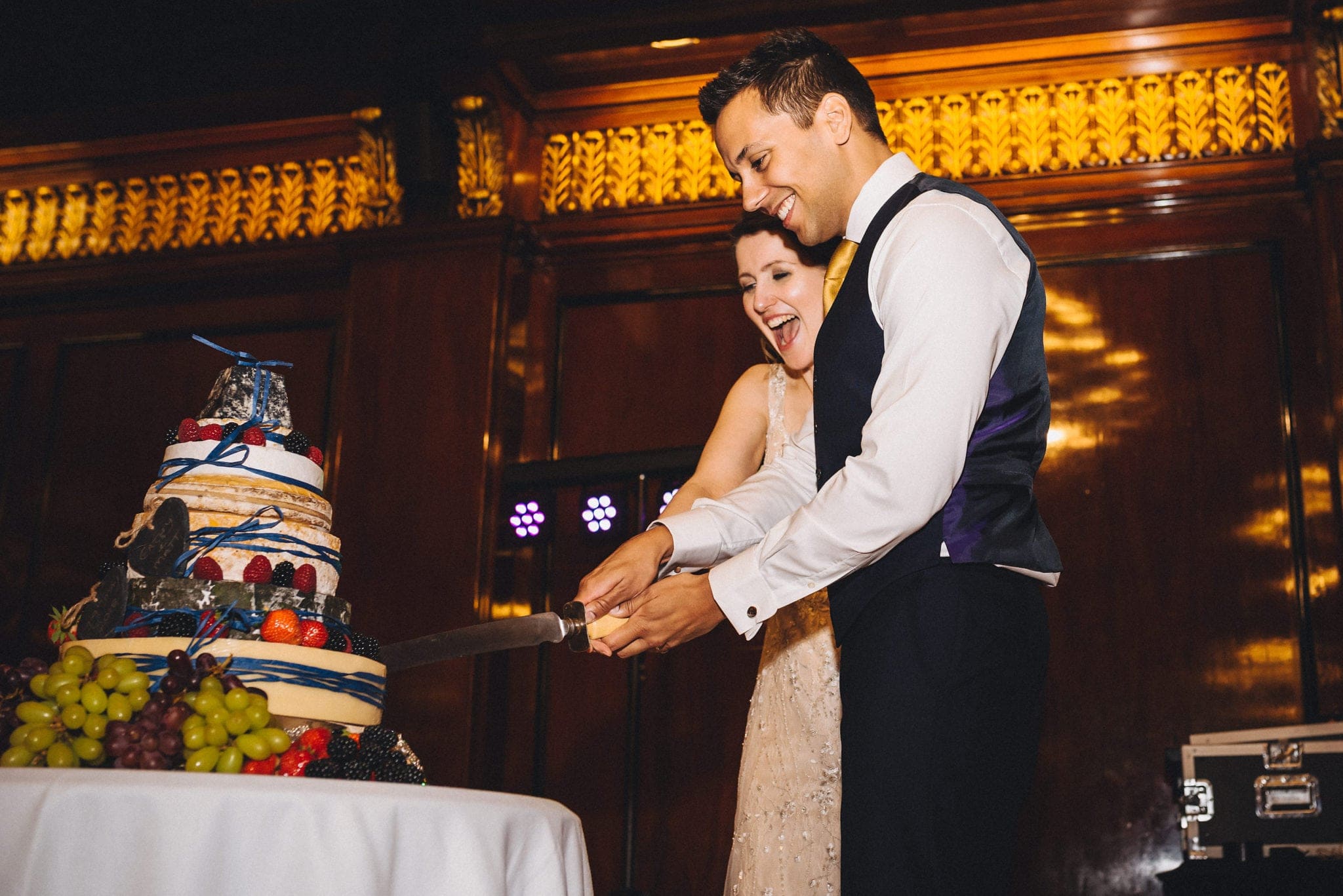 Bride and groom cut cheese wedding cake at relaxed London wedding