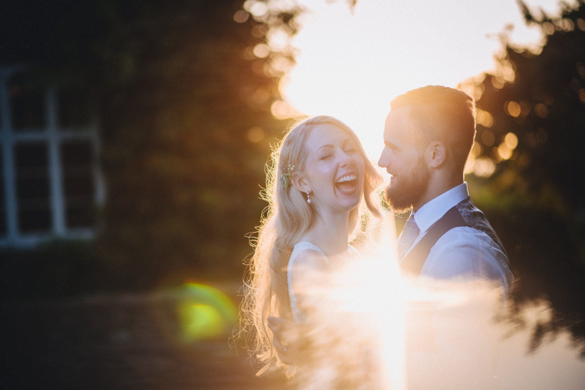 Bride and groom laughing at sunset at Dewsall Court