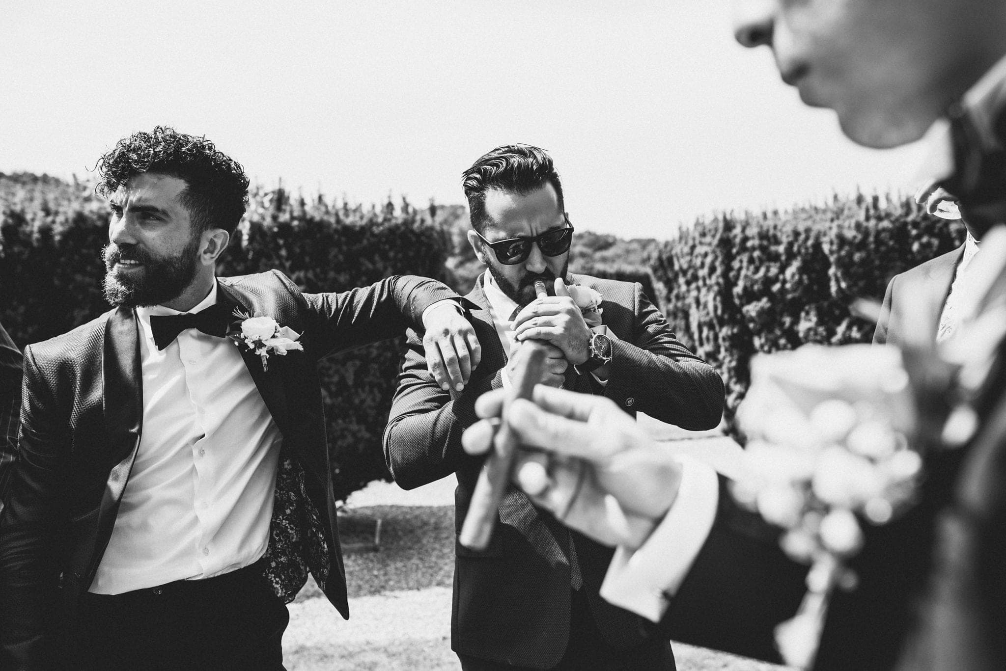 Groom and groomsmen smoking cigars in the rose garden at St Audries Park