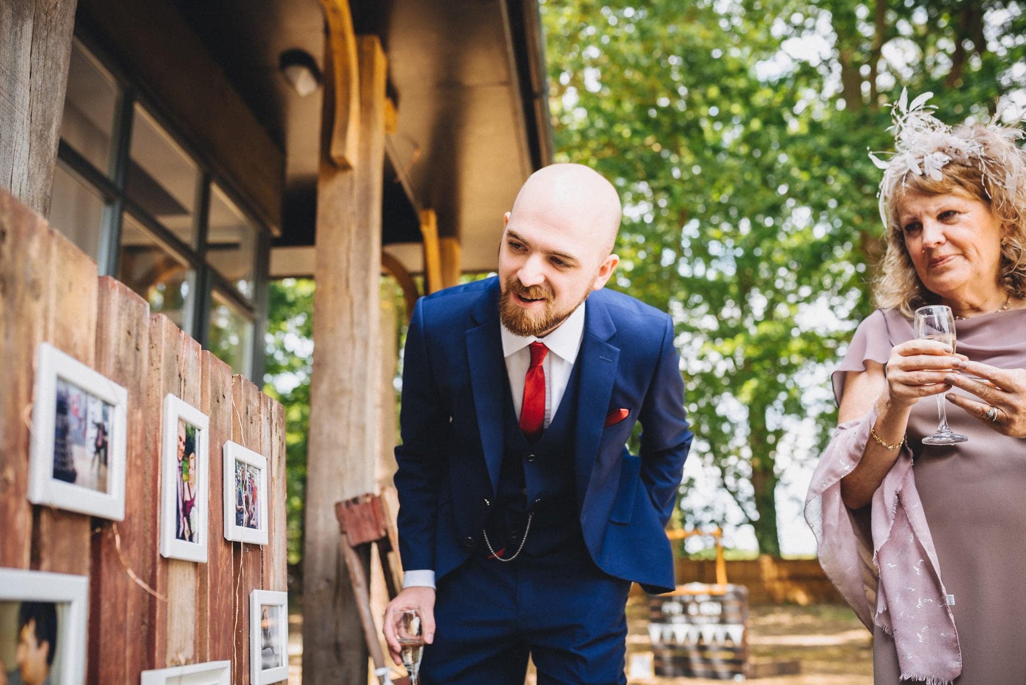 Guest bends to look at photos of the bride and groom in the courtyard of Hever Hotel